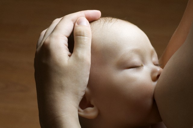 Infant child breast-feeding with eyes closed