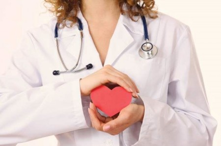 Female doctor with stethoscope holding heart